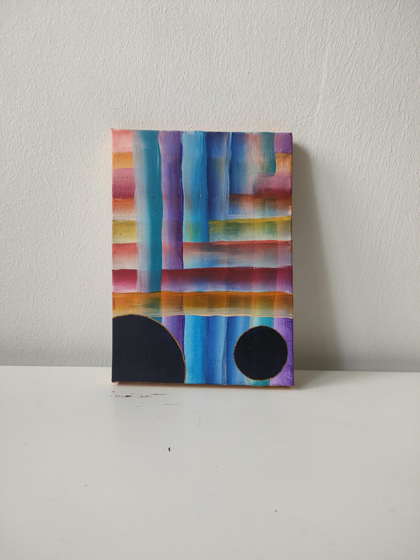Crossing bands of pink, blue, orange and violet, with two black discs at the foot of the canvas.