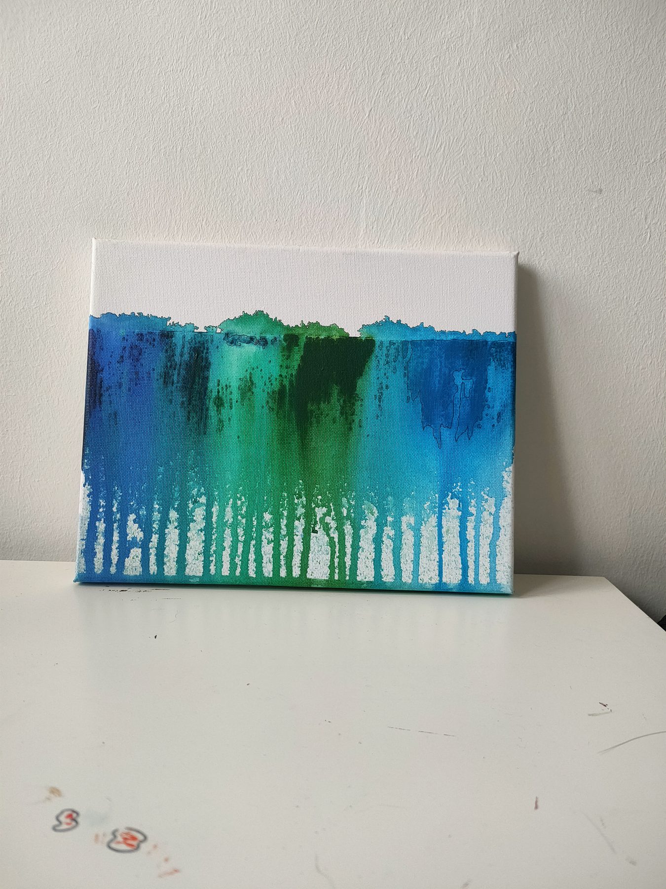 Green and blue poured down a white canvas in long drips.