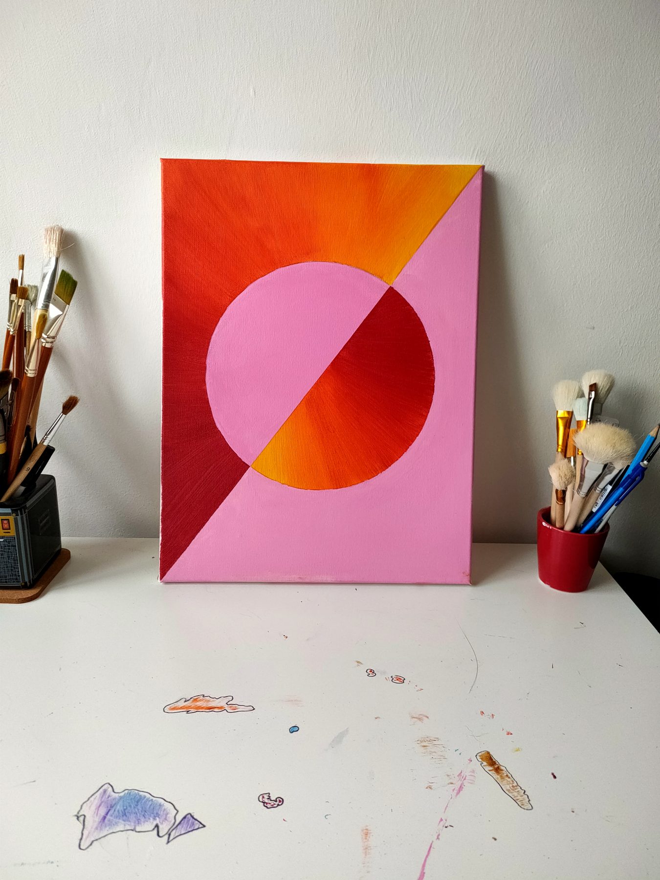A large pink circle divided by a diagonal, on a pink ground with an orange and red corner.