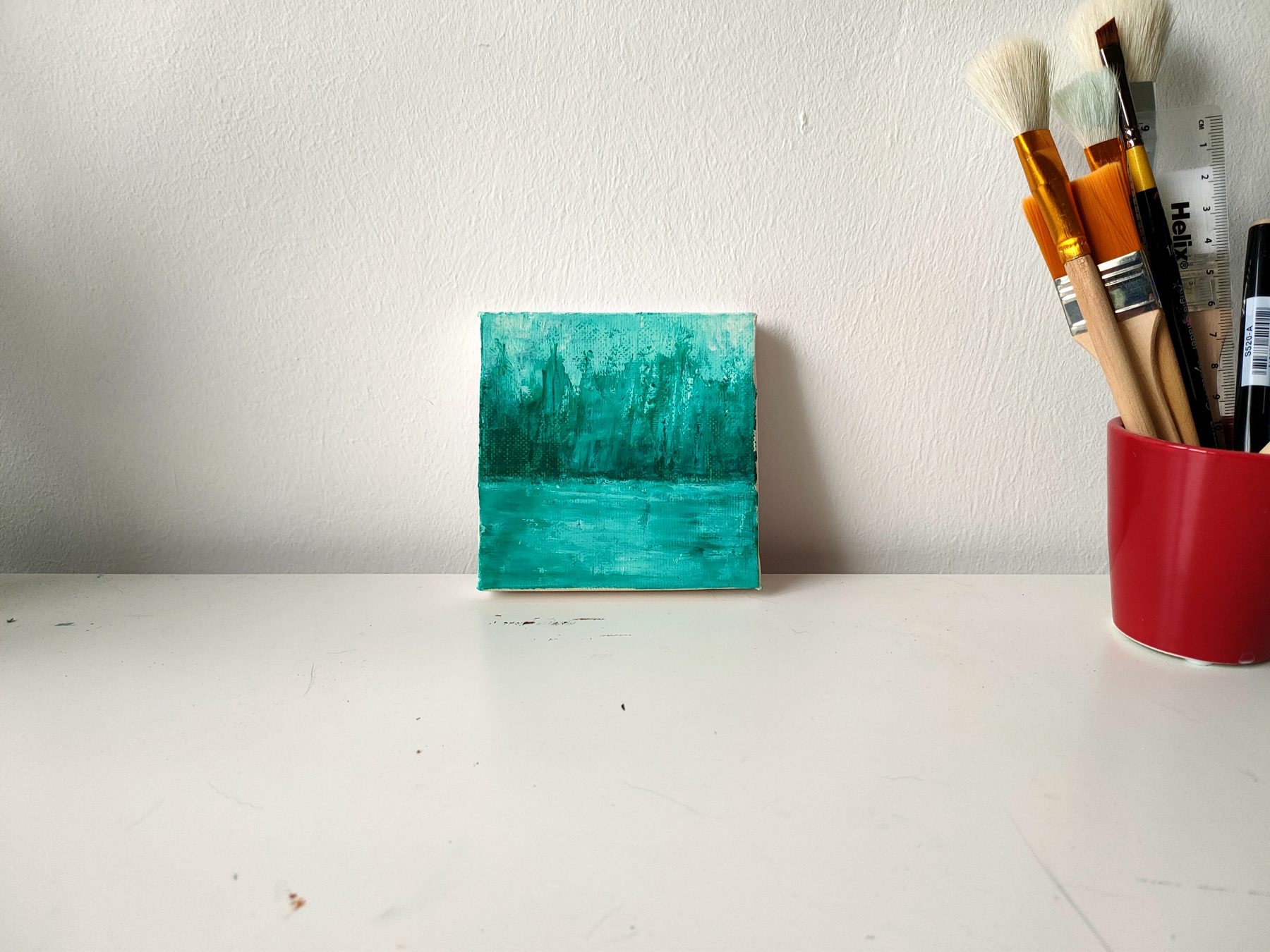 A small square of green and teal, worked in vertical strokes towards a lighter horizon.