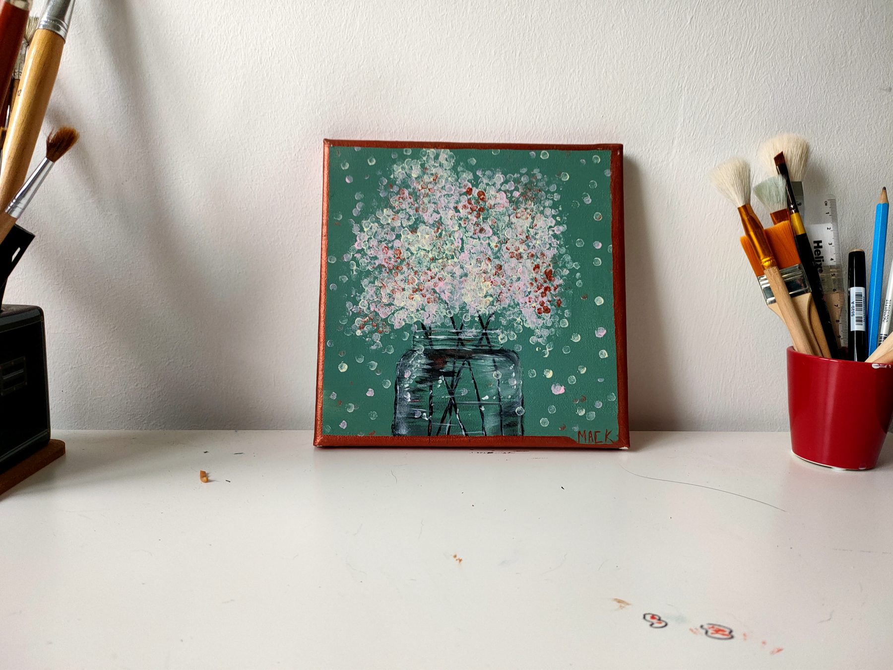White blossom scattered over a green ground above a dark structure.
