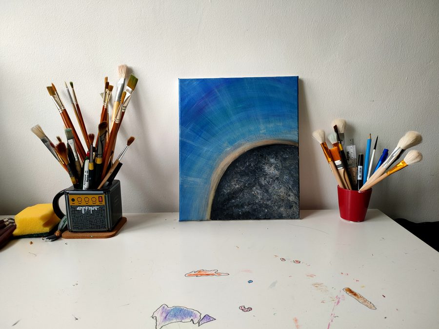 A pale arch over a dark textured centre, on deep blue.
