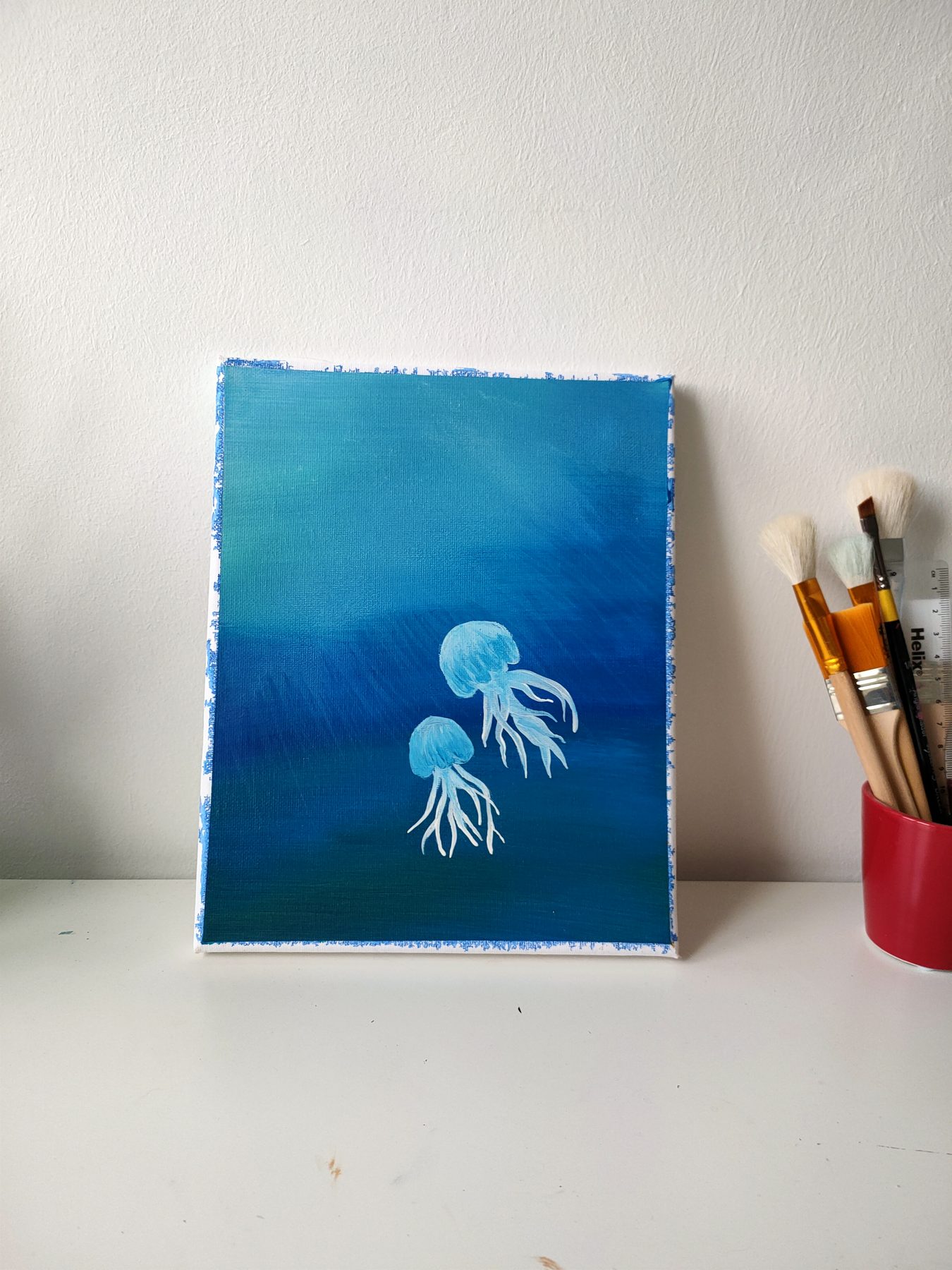 Two white jellyfish drifting in blue depth.