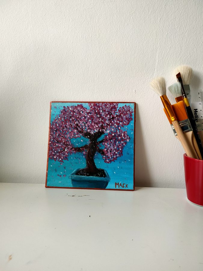A cherry blossom bonsai in a pot against a teal ground.